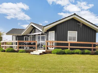 a black house with a porch and a fence at Holiday Home Eberta - 200m to the fjord by Interhome in Vinderup