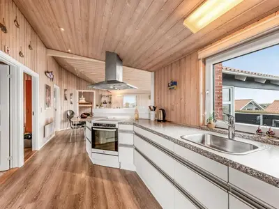 a kitchen with white cabinets and a wooden ceiling at Holiday Home Loviisa - 300m to the fjord by Interhome in Vinderup
