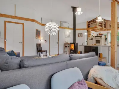 a living room with a gray couch and a kitchen at Holiday Home Flugha - 500m to the fjord by Interhome in Thyholm