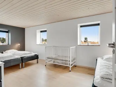 a bedroom with two beds and a crib at Holiday Home Folkar - 3km to the fjord by Interhome in Thyholm
