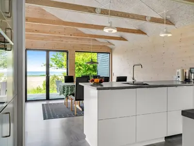 a kitchen with white cabinets and a table with chairs at Holiday Home Aslag - 150m to the fjord by Interhome in Vinderup