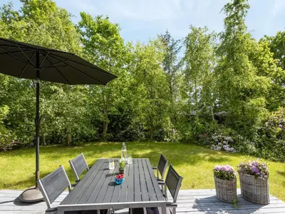 a wooden table with chairs and an umbrella at Holiday Home Alika - 200m to the fjord by Interhome in Thyholm