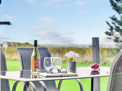 a table with a bottle of wine and glasses at Holiday Home Ginia - 150m to the fjord by Interhome in Vinderup
