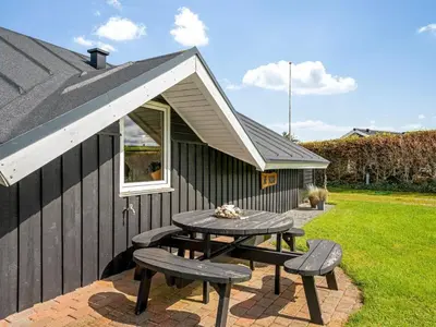 a picnic table with two benches next to a building at Holiday Home Naninja - 300m to the inlet by Interhome in Vinderup