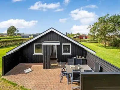 a black house with a pitched roof with a patio at Holiday Home Naninja - 300m to the inlet by Interhome in Vinderup