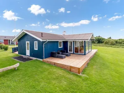 a blue house with a deck in a field at Holiday Home Titta - 150m to the fjord by Interhome in Vinderup