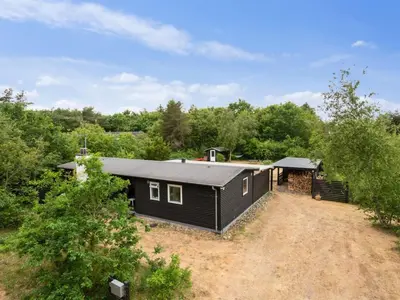 a black house in the middle of a field at Holiday Home Akke - 150m to the fjord by Interhome in Spottrup