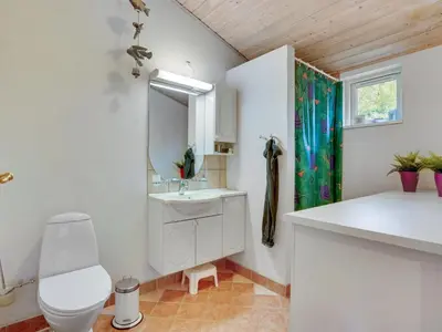 a bathroom with a sink and a toilet and a mirror at Holiday Home Blome - 150m to the fjord by Interhome in Højslev