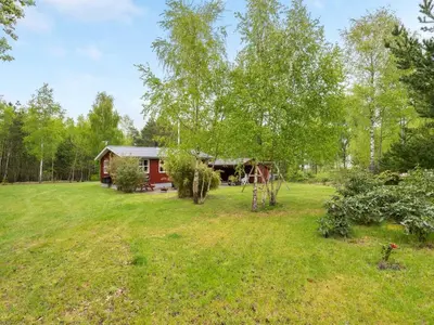 a red cabin in the middle of a grass field at Holiday Home Blome - 150m to the fjord by Interhome in Højslev