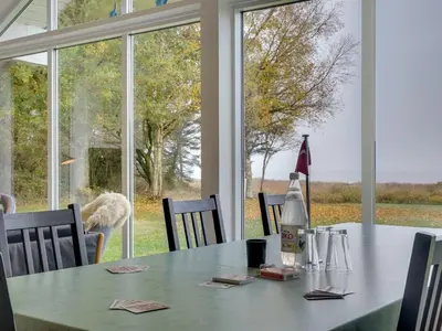 a dining room table with a dog looking out the window at Holiday Home Elis - 90m to the fjord by Interhome in Roslev