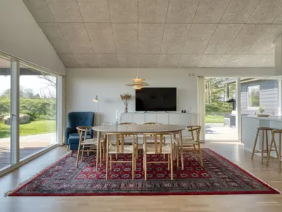 a dining room with a table and chairs on a rug at Holiday Home Elissa - 50m to the fjord by Interhome in Roslev