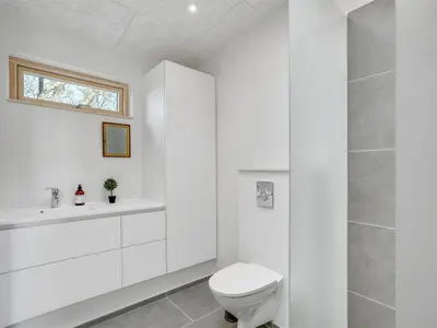 a white bathroom with a toilet and a sink at Holiday Home Haubert - 500m to the fjord by Interhome in Lihme