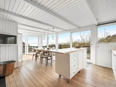 a white kitchen with a table and a dining room at Holiday Home Heera - 100m to the fjord by Interhome in Lihme