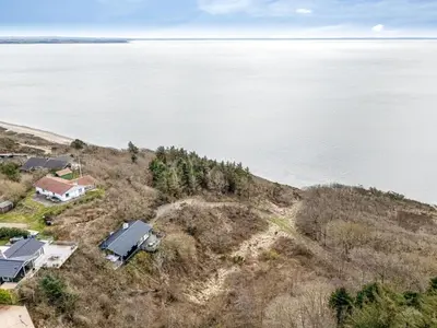an aerial view of a house on a hill next to the water at Holiday Home Heera - 100m to the fjord by Interhome in Lihme