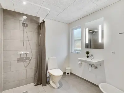 a white bathroom with a toilet and a sink at Holiday Home Sibbe - 500m to the fjord by Interhome in Spottrup