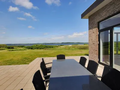 a table and chairs on a patio with a view of the ocean at Holiday Home Eloise - 50m to the fjord by Interhome in Roslev