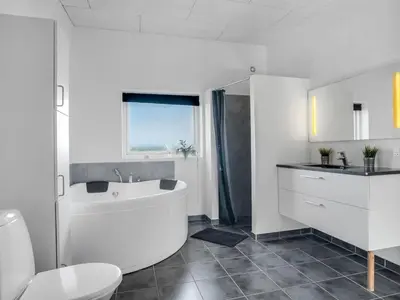 a bathroom with a tub and a toilet and a sink at Holiday Home Eloise - 50m to the fjord by Interhome in Roslev