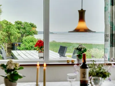 a window with a view of a table with a bottle of wine at Holiday Home Ephra - 250m to the fjord by Interhome in Roslev