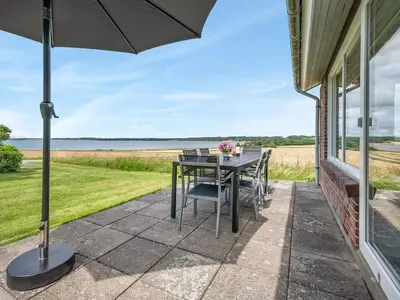 a patio with a table and chairs and an umbrella at Holiday Home Ephra - 250m to the fjord by Interhome in Roslev