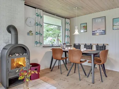 a dining room with a fireplace and a table and chairs at Holiday Home Kaleva - 200m to the fjord by Interhome in Fur