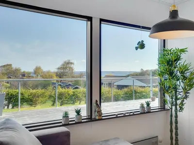 a living room with a large window with potted plants at Holiday Home Clarita - 300m to the fjord by Interhome in Roslev