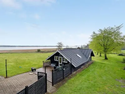 a house with a black roof and a fence at Holiday Home Henrieke - 250m to the fjord by Interhome in Roslev