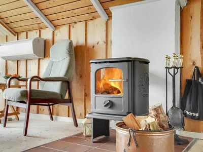 a living room with a wood stove and a chair at Holiday Home Henrieke - 250m to the fjord by Interhome in Roslev