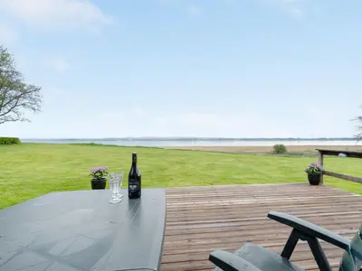a bottle of wine sitting on a table on a deck at Holiday Home Henrieke - 250m to the fjord by Interhome in Roslev