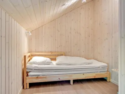 a bed in a room with a wooden wall at Holiday Home Regni - 300m to the fjord by Interhome in Nykøbing Mors