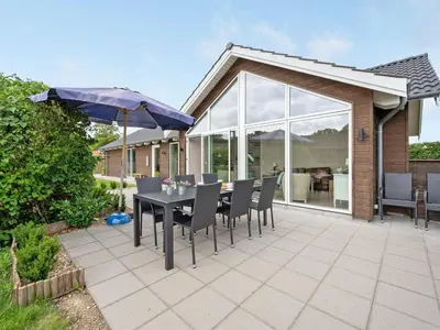 a table with chairs and an umbrella on a patio at Holiday Home Regni - 300m to the fjord by Interhome in Nykøbing Mors