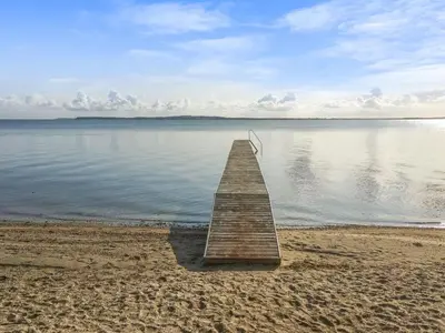 a wooden pier on a beach near the water at Holiday Home Regni - 300m to the fjord by Interhome in Nykøbing Mors