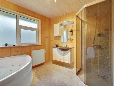 a bathroom with a tub and a shower and a sink at Holiday Home Tille - 700m to the fjord by Interhome in Roslev
