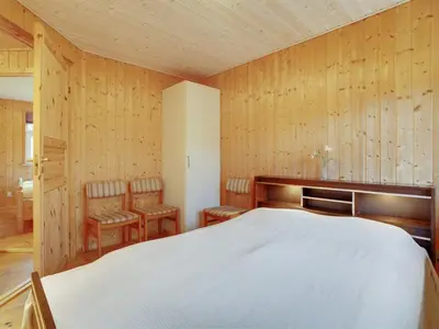 a bedroom with a white bed and wooden walls at Holiday Home Tille - 700m to the fjord by Interhome in Roslev