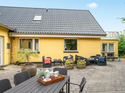 a patio with a table and chairs and a yellow house at Holiday Home Rina - 30m to the fjord by Interhome in Fur