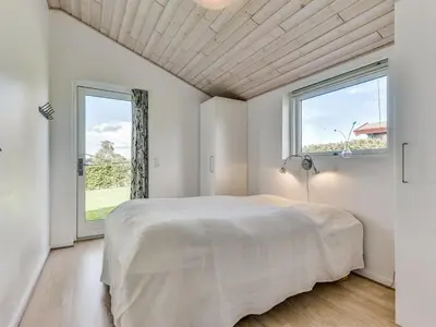 a white bedroom with a large bed and a window at Holiday Home Sylvelin - 400m to the fjord by Interhome in Roslev