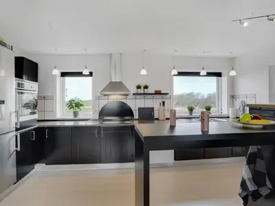 a large kitchen with black cabinets and a large island at Holiday Home Imilie - 250m to the fjord by Interhome in Redsted