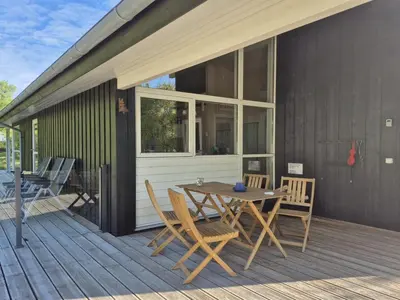 a wooden deck with a table and chairs on it at Holiday Home Aswarth - 50m to the fjord by Interhome in Fur