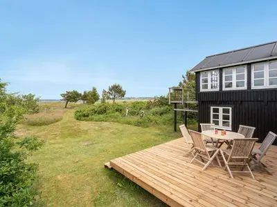 a patio with a table and chairs on a wooden deck at Holiday Home Gren - 90m to the fjord by Interhome in Roslev