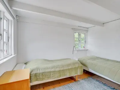 a white bedroom with two beds and a desk at Holiday Home Gren - 90m to the fjord by Interhome in Roslev
