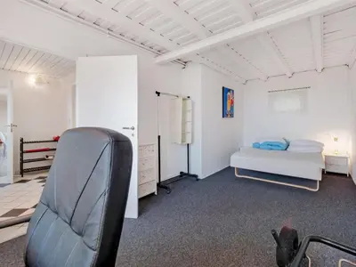 a bedroom with a bed and a chair in it at Holiday Home Emmie - 50m to the fjord by Interhome in Skarum
