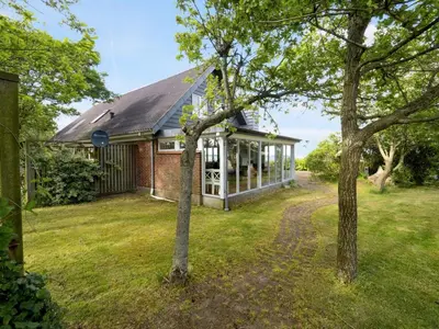 a house with a conservatory with trees in the yard at Holiday Home Emmie - 50m to the fjord by Interhome in Skarum