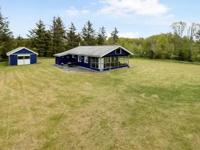 a large yard with a blue house in a field at Holiday Home Mikkeline - 400m to the fjord by Interhome in Øster Assels