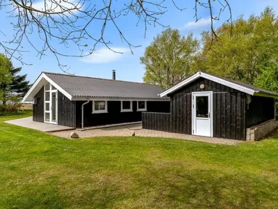 a black house with a white door and a yard at Holiday Home Eske - 200m to the fjord by Interhome in Åbybro