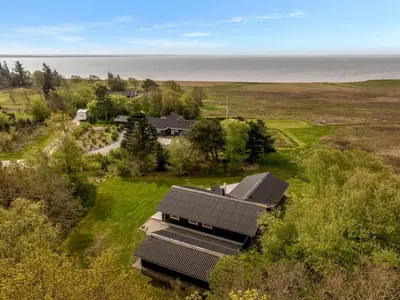 an aerial view of a house with the ocean in the background at Holiday Home Eske - 200m to the fjord by Interhome in Åbybro