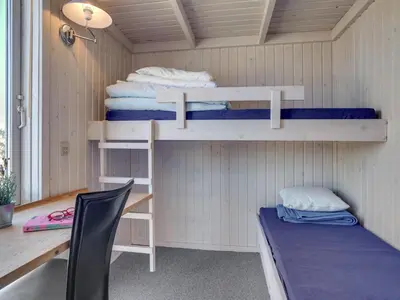a room with bunk beds and a desk and a chair at Holiday Home Fanney - 100m from the sea by Interhome in Pandrup