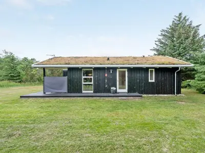 a small black house with a grass yard at Holiday Home Svantepolk - 1-1km from the sea by Interhome in Pandrup
