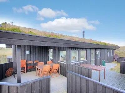 a house with a deck with a table and chairs at Holiday Home Eri - 300m from the sea by Interhome in Pandrup
