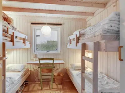 a room with bunk beds and a table and a window at Holiday Home Eri - 300m from the sea by Interhome in Pandrup