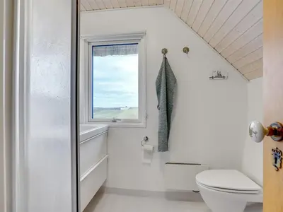 a bathroom with a toilet and a window at Holiday Home Emiline - 250m from the sea by Interhome in Saltum