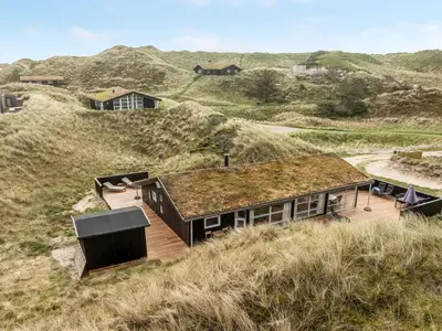 a house with a grass roof on top of a hill at Holiday Home Nielsigne - 400m from the sea by Interhome in Blokhus